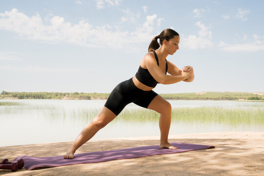 Woman practicing yoga by the lake during daytime