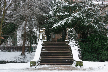 Parkowe, kamienne schody. Jest zimowy dzień. Schody, prowadząca do nich alejka jak i okoliczne drzewa pokrywa śnieg. © boguslavus