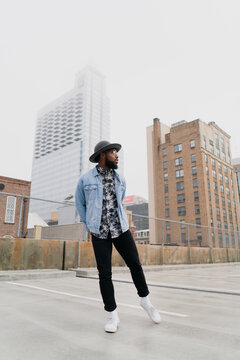 Young Man Playfully Moves on Rooftop Beneath Overcast Sky