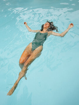 Woman Floating Peacefully in a Blue Swimming Pool During Midday