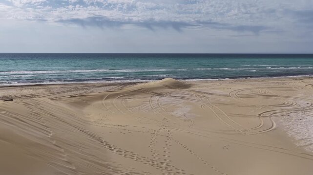 Aerial view of a sand dune landscape meeting the turquoise Caspian sea