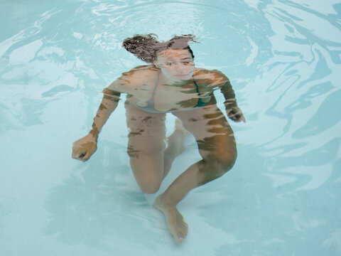 Young Woman Swimming Underwater in a Clear Pool