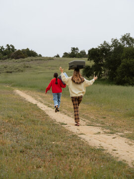 Two Friends Walking on a Dirt Path in a Green Field During Daylight