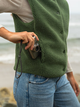 Person Wearing Green Vest Retrieves Camera on Beach 