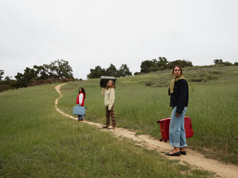 Three Travelers Walking Down a Path in a Green Landscape