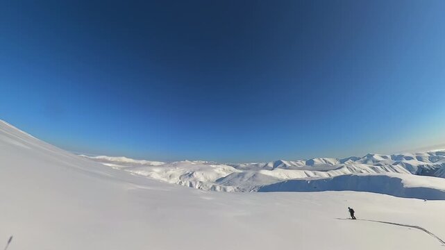A Solo Skier Glides Down a Vast, Powder-Covered Mountain Slope During an Epic Heliskiing Adventure