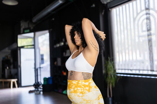 Pregnant woman stretching arms in a gym