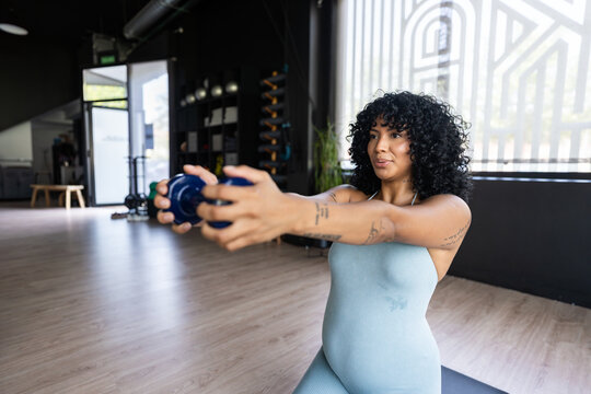 Pregnant woman exercising with small dumbbell at the gym