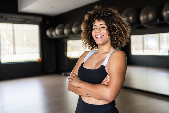 Transgender woman smiling with crossed arms in gym