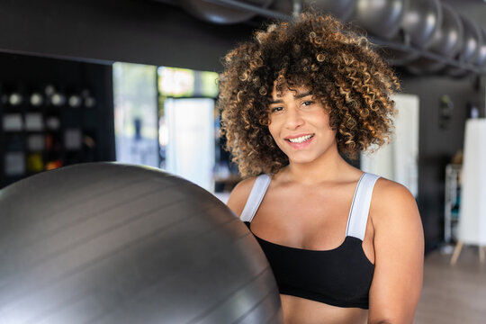 Smiling fitness instructor holding pilates ball in gym