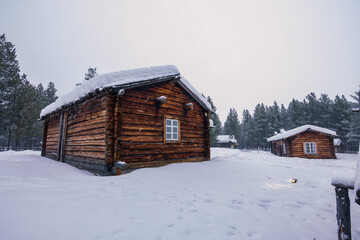 Traditional red wooden cabin covered in deep snow in the forest of Inari, Finnish Lapland.