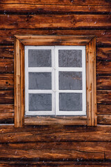 Traditional red wooden cabin covered in deep snow in the forest of Inari, Finnish Lapland.
