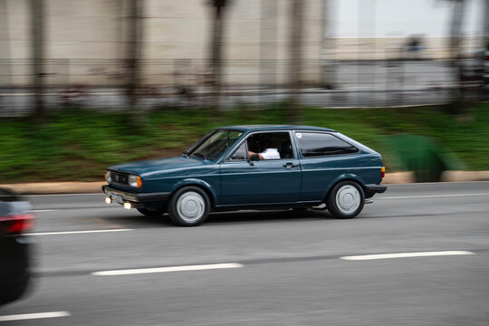 Blue Volkswagen Gol GT side view panning shot, Vintage hot hatch driving on city street