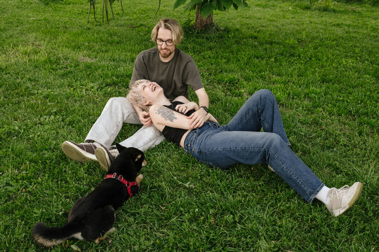 Happy Couple Relaxing in Park with Their Shiba Inu