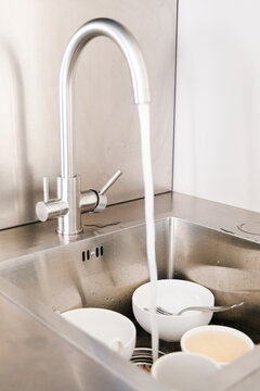 Running Water Over Piled Dishes in Sink
