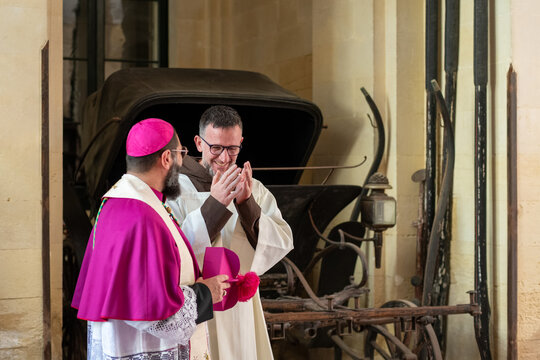 Clergy Members Interact Near Historical Carriage in Old Building