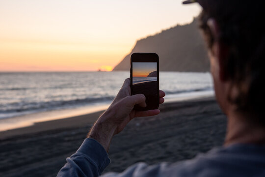 Man Taking Photo of Beautiful Sunset on California Beach 