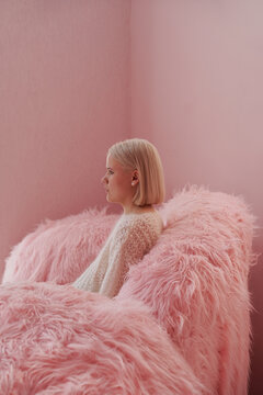 Woman seated on pink fluffy sofa in cozy indoor space
