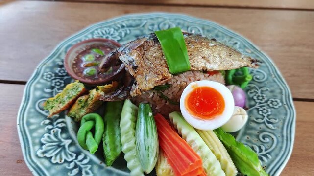 Thai fried rice with shrimp paste, topped with fried mackerel, vegetables, and egg.