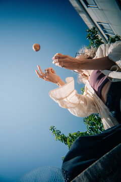 Woman Juggling Under a Clear Blue Sky With Greenery Surrounding
