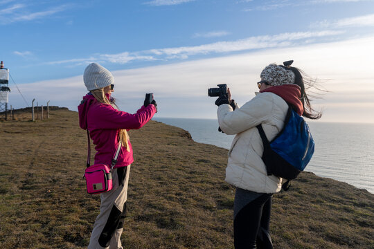 Friends Capturing Memories on a Scenic Cliffside During Sunset