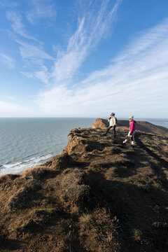 Two Hikers Explore Coastal Cliffs Under a Clear Sky