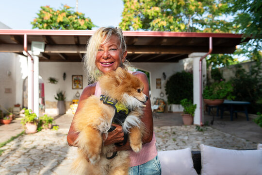 Woman Embraces Fluffy Dog in a Home Garden