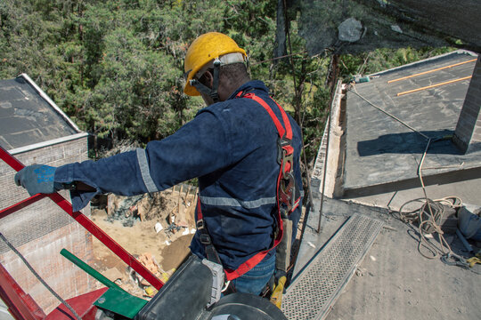 Construction worker balancing on high rooftop with safety gear