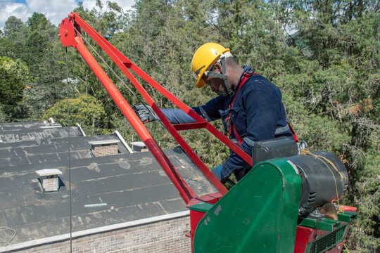Worker operates equipment for maintenance on building rooftop