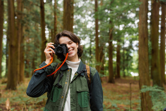 A woman takes pictures in the woods
