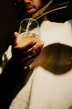 Low Angle Shot of Black Man Pouring a Glass of Wine with Dynamic Light