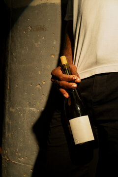 Close Up of Black Man Leaning Against Wall Holding a Bottle of Wine