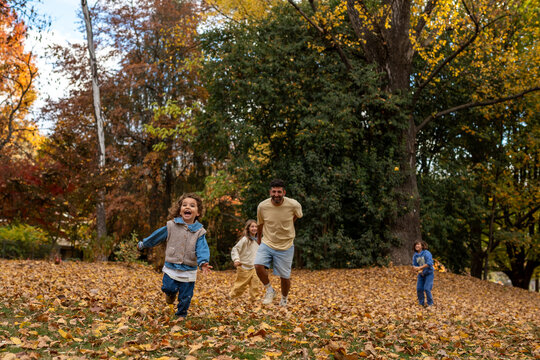 Family Running Through Autumn Leaves in the Park