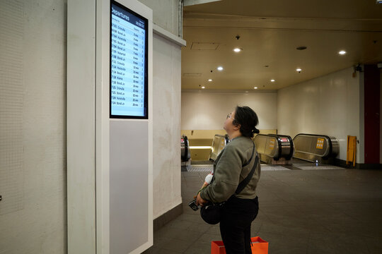 Passenger Checking Train Schedule at a Sydney Station in the Evening