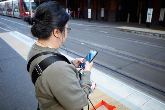 Woman Waiting at Tram Stop in Sydney CBD While Using Smartphone