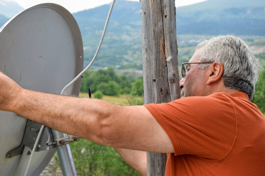 Man Adjusting Satellite Dish in Scenic Mountains