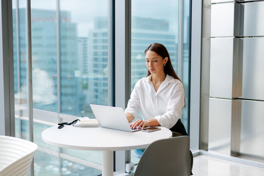 Businesswoman Using Laptop in High-Rise  in Modern Office