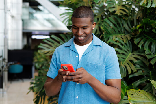Smiling Businessman Using Red Mobile Device in Modern Office Garden
