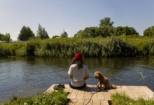 Person and dog enjoy a quiet moment by the river on a sunny day