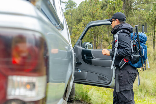 Hiker getting out of his pickup truck in the forest during road trip