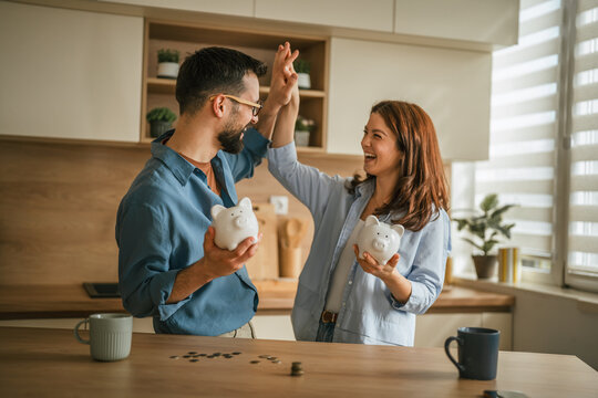 Happy couple achieving financial goals with piggy banks