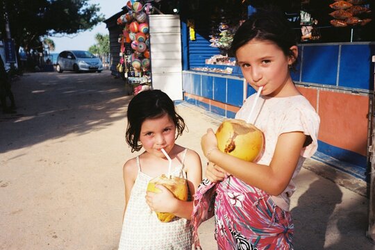 Children Enjoy Fresh Coconuts at Tropical Market. Film