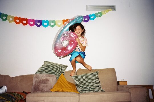 Girl Jumping on Couch Celebrating Sixth Birthday. Film 
