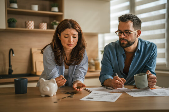 Couple worrying about finances, counting coins from piggy bank
