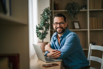 Fototapeta premium Man smiling working from home office on laptop