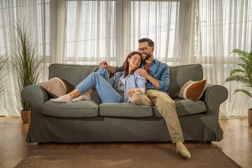 Obraz premium Happy young couple relaxing together on living room sofa