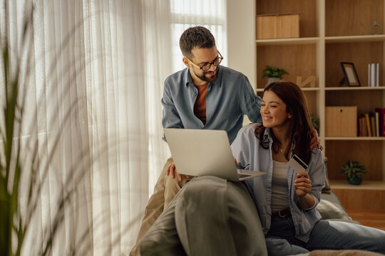 Young happy couple shopping online using laptop and credit card