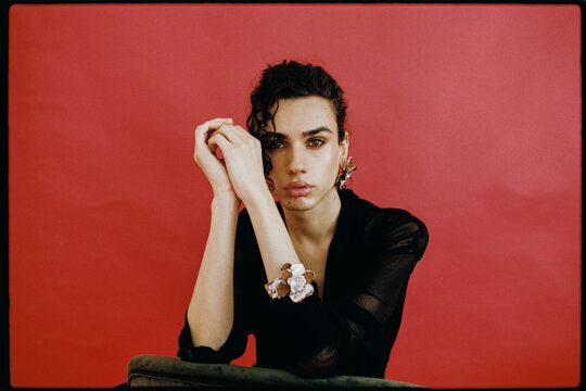 Queer man posing with hands together wearing jewelry