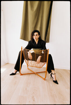 Man posing on orange metal chair in studio