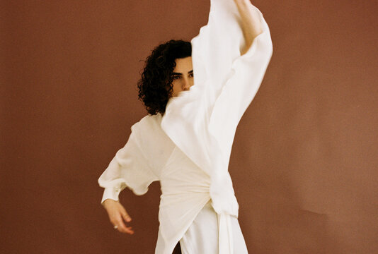 Model wearing white dress, posing dynamically 